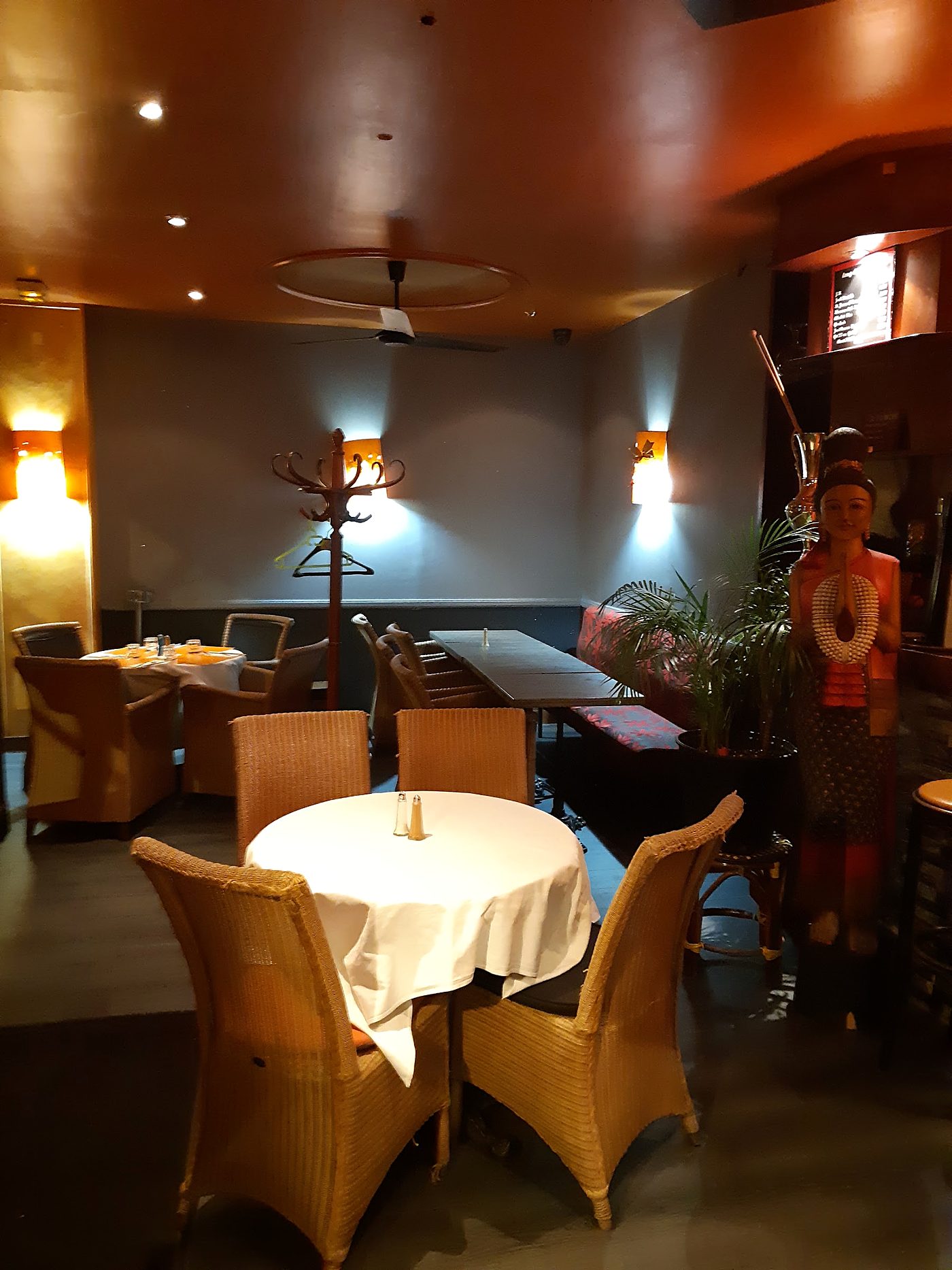 La salle du Blue Buoi le soir, tables dressées et fauteuils en rotin.